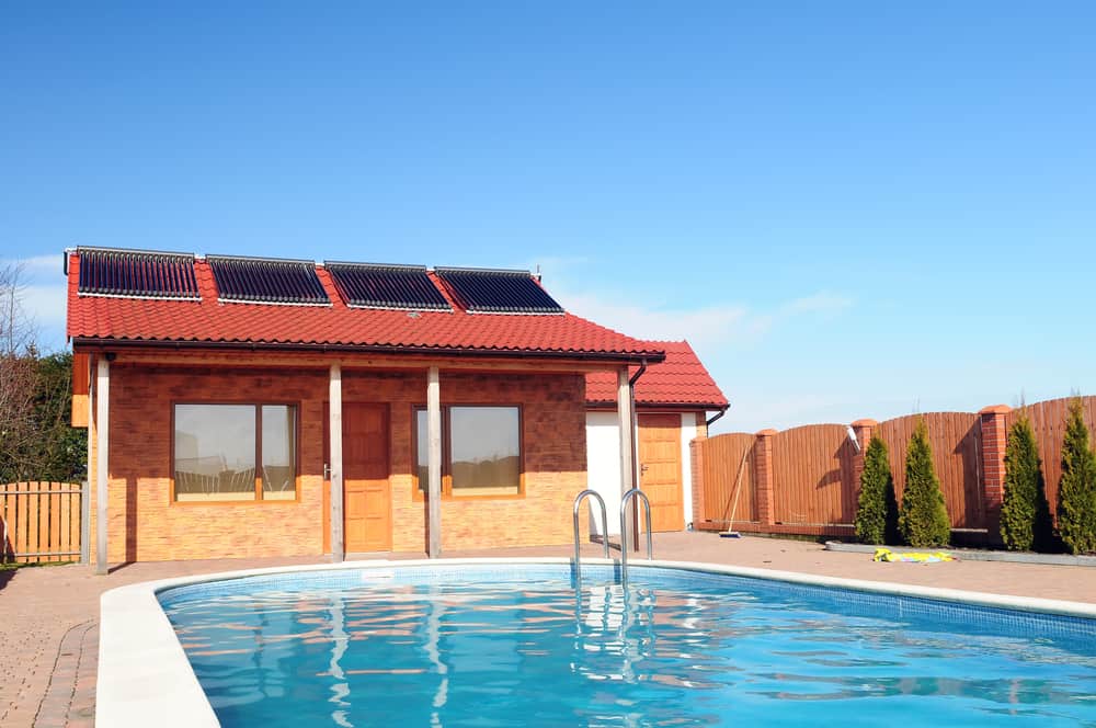 Solar heating array on roof of bungalow behind swimming pool - Heating your Pool? - Go Solar