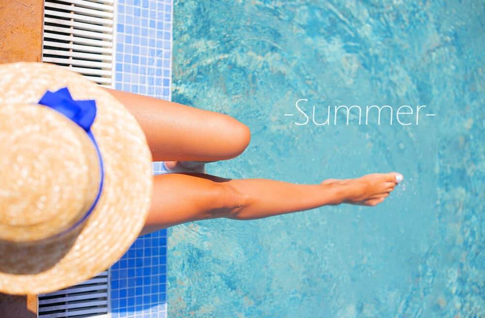 A young woman relaxing on a pool side lounge under a hat - Summer in the Pool - Tips and Tricks