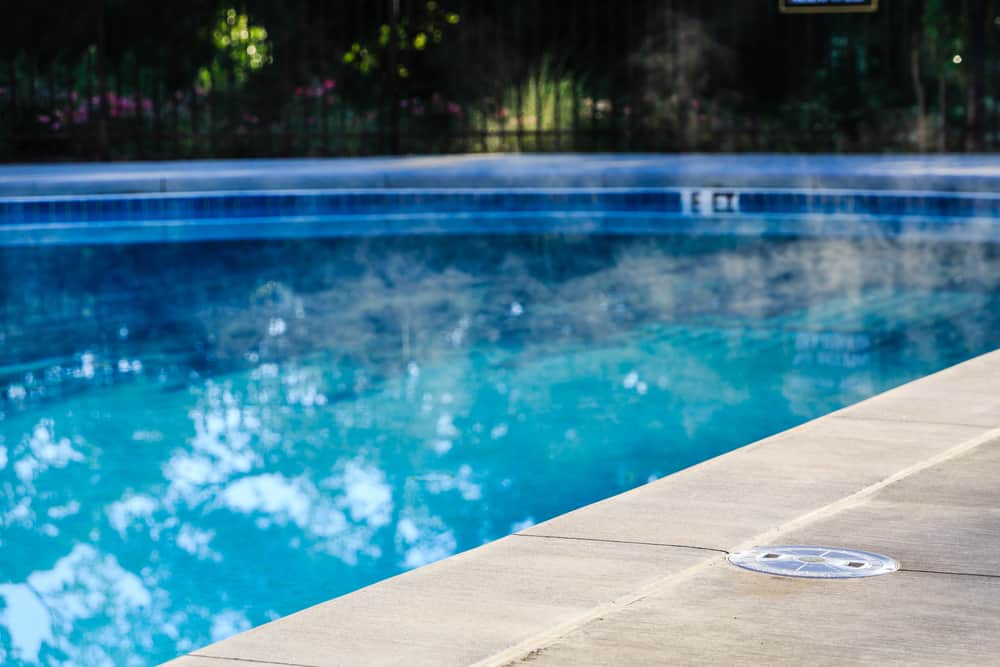 Steam Rising from Heated Swimming Pool with Concrete Deck - Why You Should Get a Professional Heating Consultation