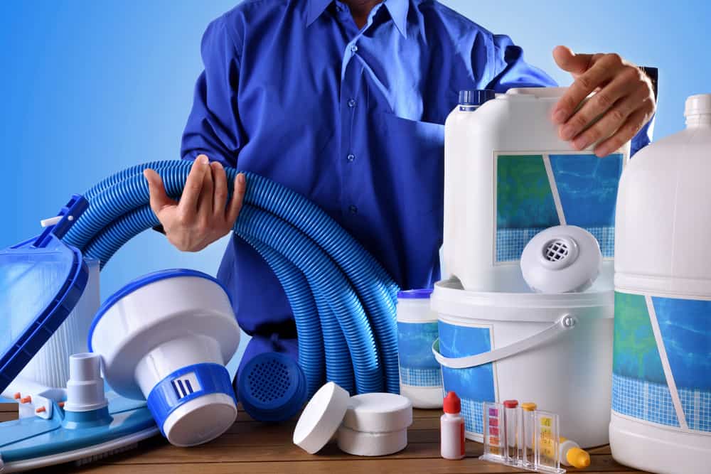 Swimming pool maintenance worker with chemical cleaning products and tools on wood table and blue background. Horizontal composition. Front view - Maintenance and Servicing for your Pool Heating
